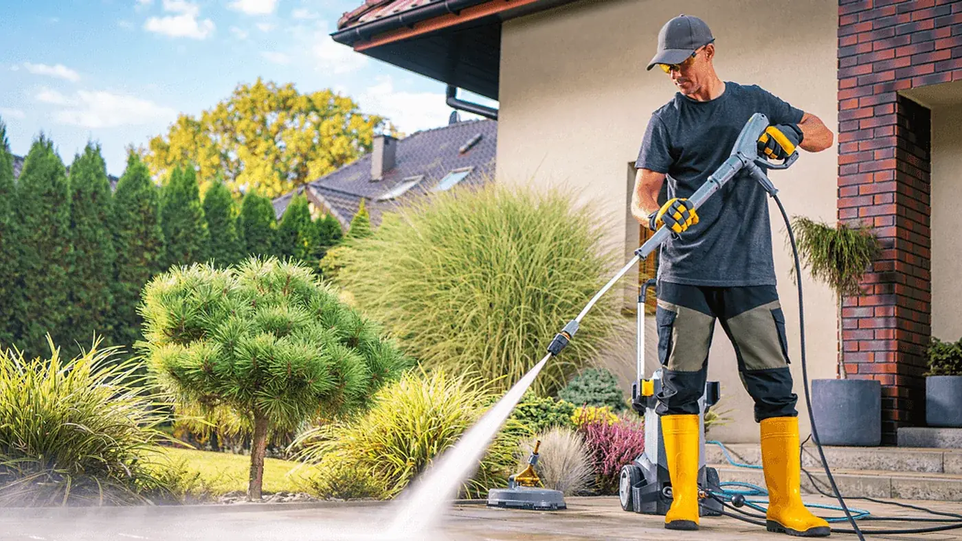 Pressure cleaning technician washing a paver driveway outside a Jacksonville FL home